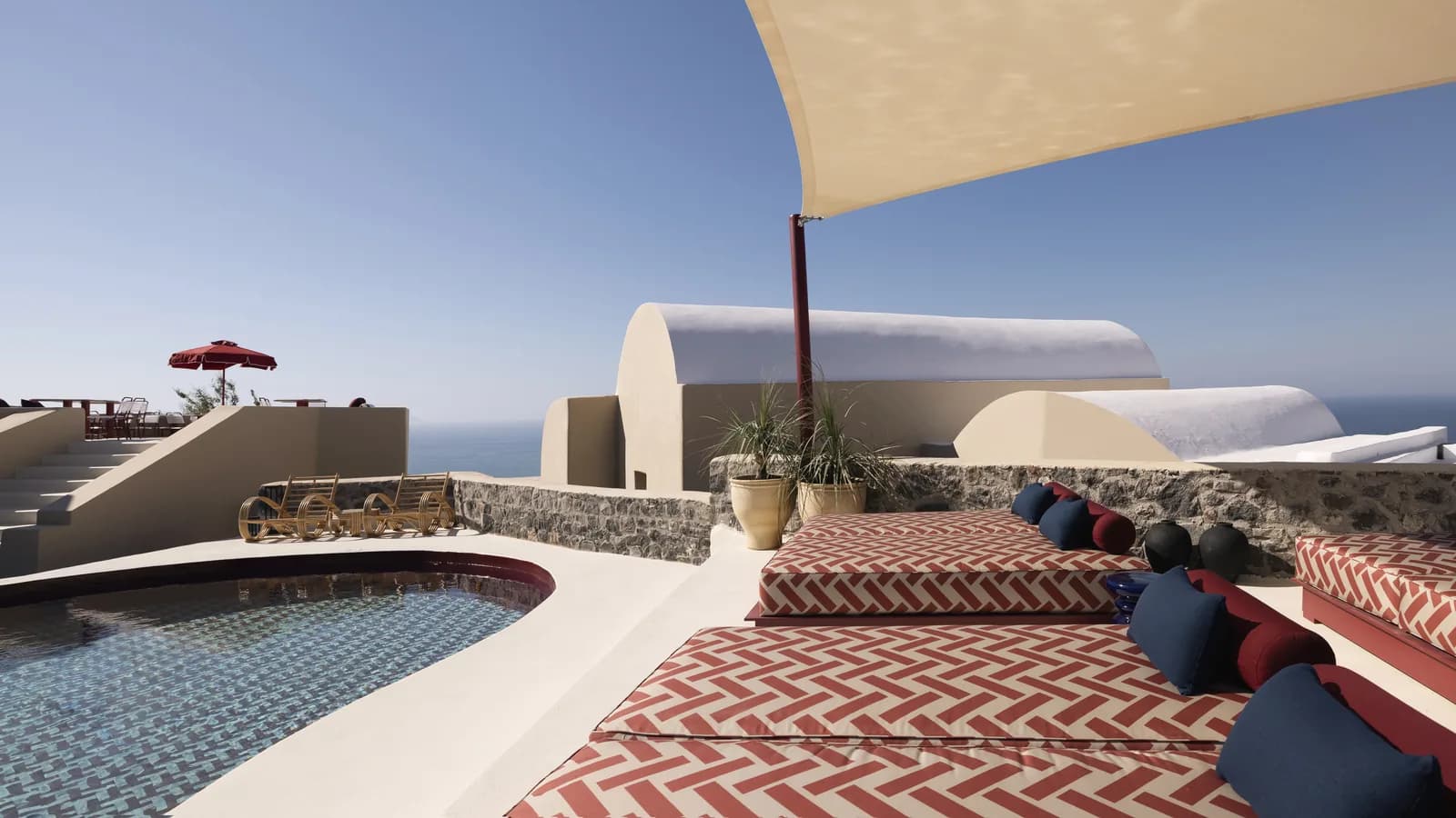 Pool und Terrasse des Neema Maison mit Polstern, Sonnensegel und Blick aufs Meer