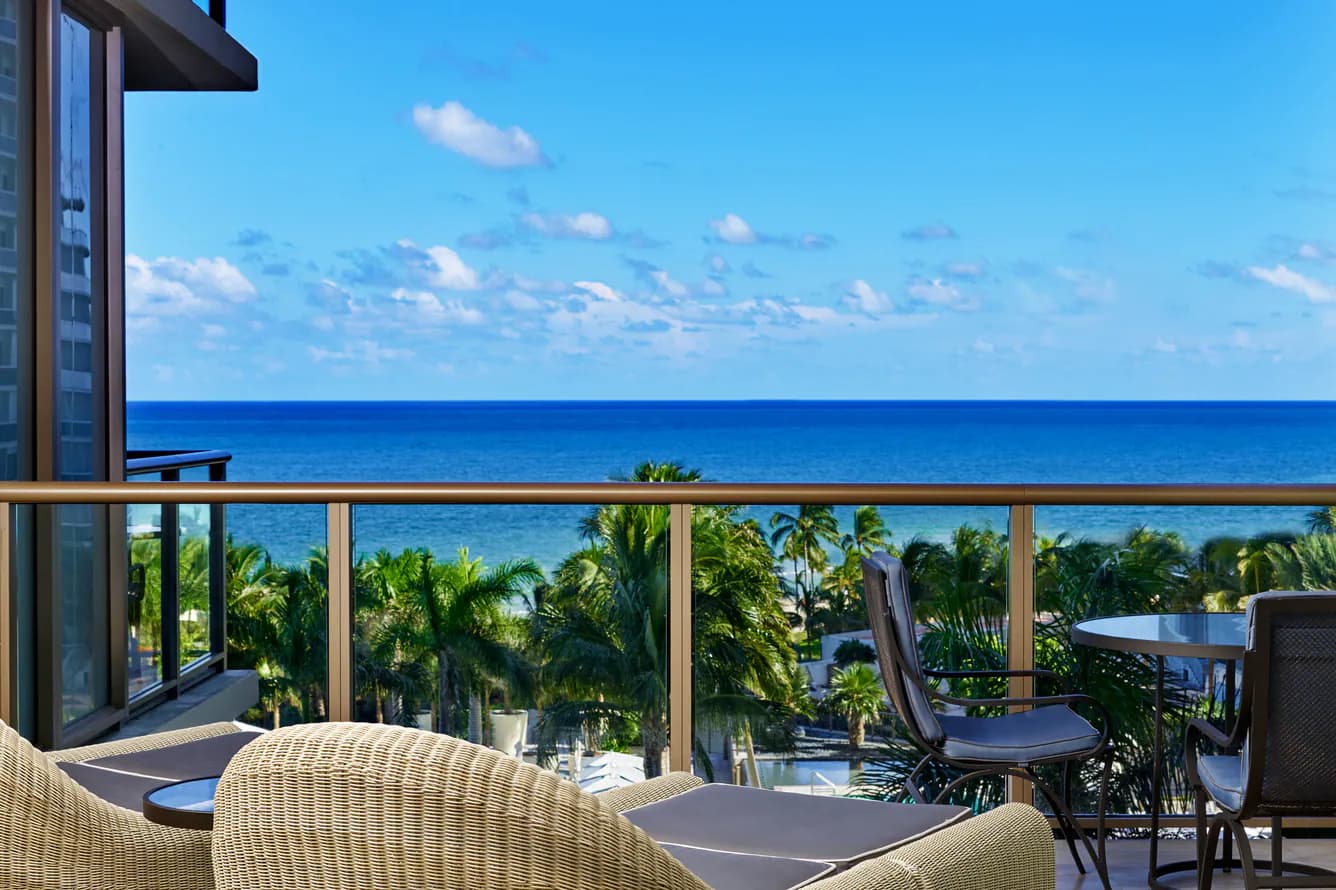 St. Regis Bal Harbour – Balkon mit Korbsesseln, darunter die Palmen des Resorts und dahinter der Atlantik