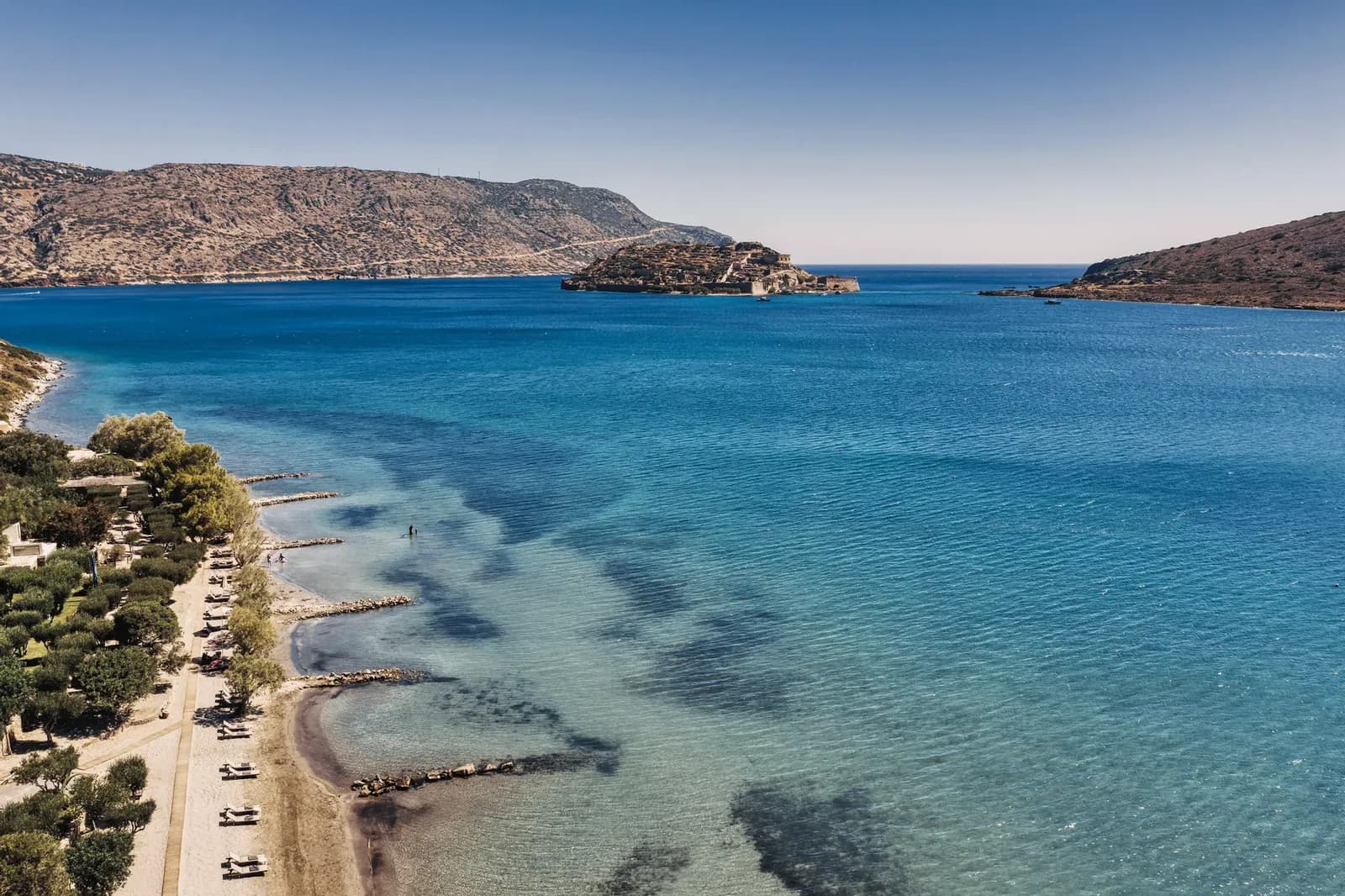 Die Bucht von Elounda aus der Luft mit Sandstrand, türkisfarbenem Wasser und der Insel Spinalonga